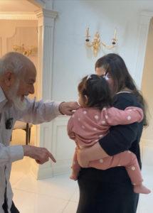 Baby niece in her mother’s arms playing with grandfather, symbolizing love and strength.