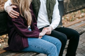 couple siting on a bench and holding hands